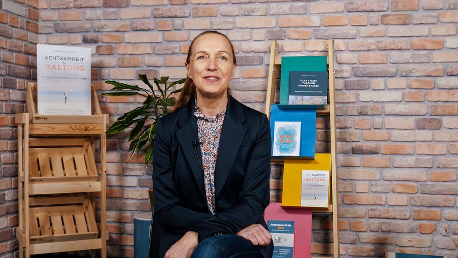 Gabriele Andler bei einem Interview auf der Buchmesse Leipzig. Im Hintergrund ein Messestand mit Büchern des Verlags Attention.rocks.